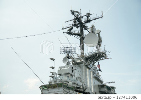 A detailed view of the communication and radar tower aboard the USS Intrepid, located at the Intrepid Sea, Air, Space Museum in New York City. The structure features antennas, satellite dishes, and 127411006