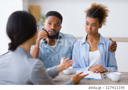 Serious Young Afro Couple Listening To Their Investment Counselor During Financial Consultation In Office. Selective Focus 127411195