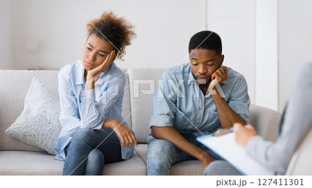 Tired of relationship. Upset african american couple sitting on couch at marital therapist's office. Selective focus 127411301