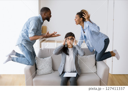 Marriage Crisis. Overwhelmed Psychologist Watching Her Afro Patients Quarrelling In Office. Selective Focus 127411337