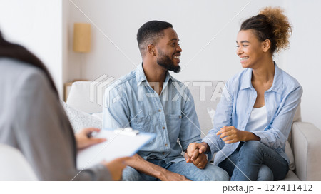 Gladful African American Couple Smiling And Laughing On Sofa After Effective Marital Therapy. Selective Focus Gladful African American Couple Smiling And Laughing On Sofa After Effective Marital Therapy. Selective Focus 127411412
