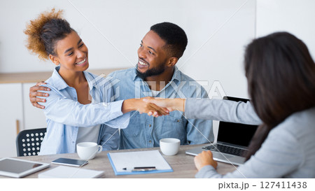 Budget planning. Positive afro couple handshaking with investment counselor in office. Selective focus Budget planning. Positive afro couple handshaking with investment counselor in office. Selective focus 127411438