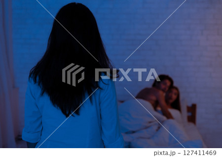 Cheating And Infidelity. Girlfriend Catching Unfaithful Boyfriend With Another Woman Lying In Bed At Home. Low Light 127411469
