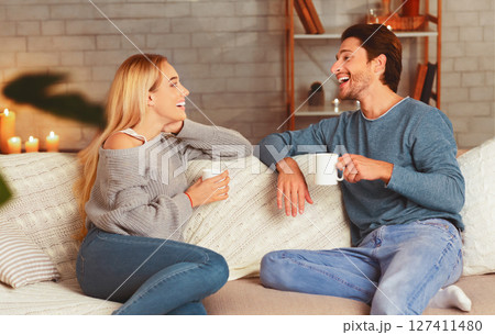 Happy Couple Enjoying Conversation Having Coffee Sitting On Couch At Home. Selective Focus Happy Couple Enjoying Conversation Having Coffee Sitting On Couch At Home. Selective Focus 127411480