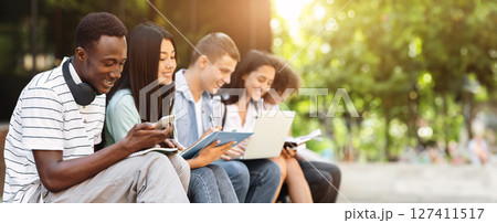 Multiethnic students having fun, studying together for exams outdoors in campus, chatting and smiling during break in classes Multiethnic students having fun, studying together for exams outdoors in campus, chatting and smiling during break in classes 127411517