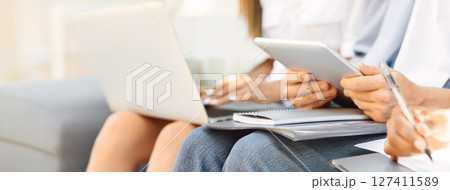 Unrecognizable Male Student Using Digital Tablet, Preparring For Classes, Browsing Interner While Sitting With University Friends Outdoors, Closeup Unrecognizable Male Student Using Digital Tablet, Preparring For Classes, Browsing Interner While Sitting With University Friends Outdoors, Closeup 127411589