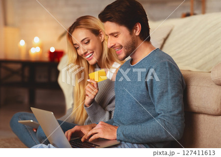 Online Order. Boyfriend And Girlfried Holding Laptop And Credit Card Shopping On The Internet Sitting Indoor. Selective Focus 127411613