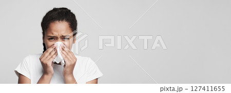Sickness, illness, virus concept. Teen black girl blowing nose over grey studio background 127411655