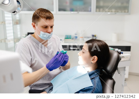 Dentist showing dental mold to young patient in clinic 127412342