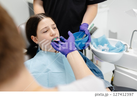 Dentist applying dental sealant on teeth of teenage girl 127412397