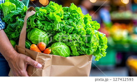 A person holding a paper bag full of fresh vegetables A person holding a paper bag full of fresh vegetables 127412593