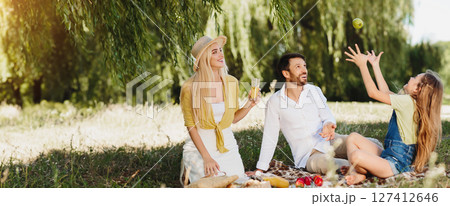 Family having picnic in nature, girl juggling with apple, enjoying weekends with parents 127412646