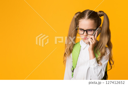Sulky School Girl Talking On Cellphone With Strict Parents Standing On Yellow Background. Studio Shot, Free Space Sulky School Girl Talking On Cellphone With Strict Parents Standing On Yellow Background. Studio Shot, Free Space 127412652