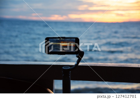 Smartphone mounted on gimbal captures sunset over ocean 127412701