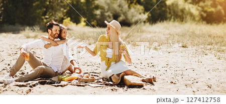 Young family enjoying picnic, sitting on blanket in nature, spending time together Young family enjoying picnic, sitting on blanket in nature, spending time together 127412758