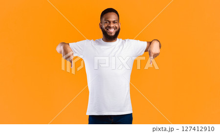 African American Guy Pointing Fingers Down Advertising Something Standing Posing In Studio Over Yellow Background, Smiling To Camera. Advertisement Banner, Look There Concept. Panorama African American Guy Pointing Fingers Down Advertising Something Standing Posing In Studio Over Yellow Background, Smiling To Camera. Advertisement Banner, Look There Concept. Panorama 127412910