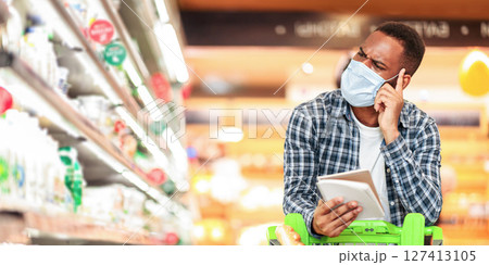 African Husband In Protective Mask Doing Grocery Shopping With Checklist Buying Food Stuff Standing With Shop Cart In Supermarket. Buyer Choosing Products In Store. Free Space For Text African Husband In Protective Mask Doing Grocery Shopping With Checklist Buying Food Stuff Standing With Shop Cart In Supermarket. Buyer Choosing Products In Store. Free Space For Text 127413105