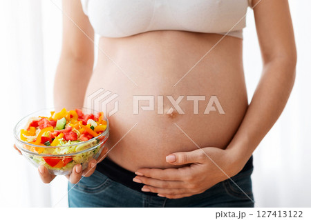 Healthy Food For Future Baby. Unrecognizable Pregnant Woman Holding Bowl With Vegetable Salad And Touching Her Naked Belly, Enjoying Organic Nurtition During Pregnancy, Closeup Shot, Cropped Healthy Food For Future Baby. Unrecognizable Pregnant Woman Holding Bowl With Vegetable Salad And Touching Her Naked Belly, Enjoying Organic Nurtition During Pregnancy, Closeup Shot, Cropped 127413122