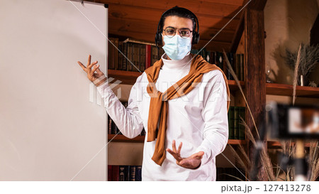 Indian Teacher In Face Mask Making Video Lecture For Educational Blog Teaching English Language Online, Pointing At Blackboard Explaining Grammar Standing Indoor. Distance Teaching And Education Indian Teacher In Face Mask Making Video Lecture For Educational Blog Teaching English Language Online, Pointing At Blackboard Explaining Grammar Standing Indoor. Distance Teaching And Education 127413278