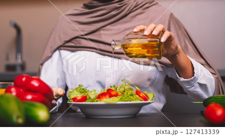 Muslim Woman Cooking In Kitchen, Making Vegetable Salad With Oil Dressing At Home, Wearing Hijab Headscarf. Arabic Wife Preparing Healthy Dinner Working Indoor. Arab Cuisine, Recipes. Cropped Muslim Woman Cooking In Kitchen, Making Vegetable Salad With Oil Dressing At Home, Wearing Hijab Headscarf. Arabic Wife Preparing Healthy Dinner Working Indoor. Arab Cuisine, Recipes. Cropped 127413339