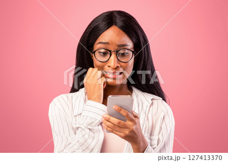Oops. Embarassed black woman looking at mobile phone screen in confusion on pink studio background. Emotional African American lady making mistake while working in web Oops. Embarassed black woman looking at mobile phone screen in confusion on pink studio background. Emotional African American lady making mistake while working in web 127413370