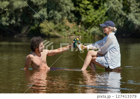Woman and man on a river with bottle of wine and beer 127413379
