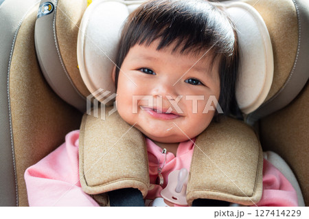 Joyful one year old asian girl smiling in car seat lifestyle moment bright environment 127414229