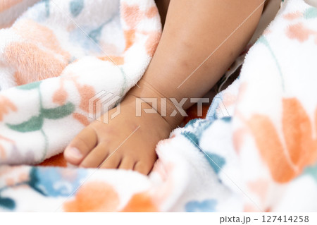 One year old asian girl's tiny foot cozy blanket indoor setting child's playful moment One year old asian girl's tiny foot cozy blanket indoor setting child's playful moment 127414258