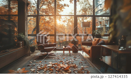 A cozy living room with large windows overlooking a vibrant autumn forest, showcasing a leather armchair and sofa with scattered leaves on the floor. 127414335