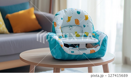 A blue and white high chair with a tray sits on a wooden table A blue and white high chair with a tray sits on a wooden table 127415689