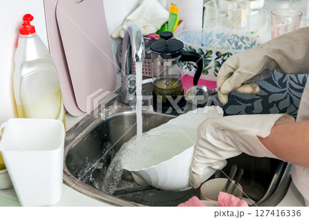 Woman washing dishes in the kitchen Woman washing dishes in the kitchen 127416336