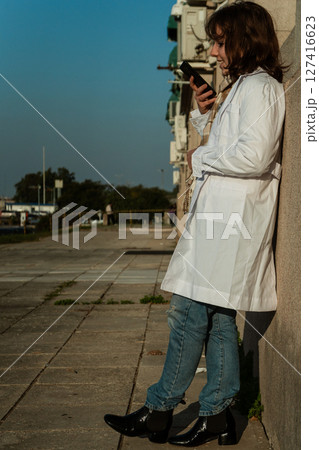 Female doctor looking at smartphone during outdoor break Female doctor looking at smartphone during outdoor break 127416623