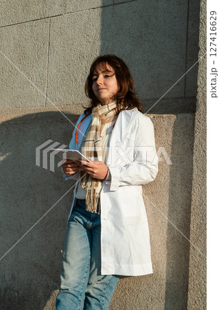 Doctor holding tablet walks across sidewalk in front of medical center Doctor holding tablet walks across sidewalk in front of medical center 127416629