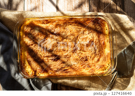 Glass platter with a meat or shepherd's pie on a rustic country table. 127416640