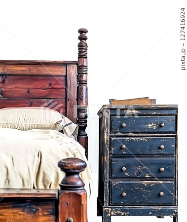 A bed with a white pillow sits next to a black dresser 127416924