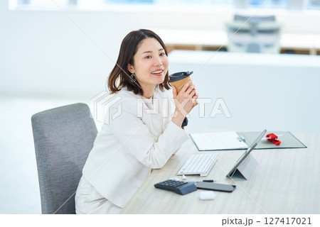 仕事中にコーヒーを飲んで休憩する女性 127417021