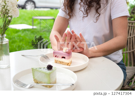 Woman Gesturing Near Colorful Cakes on White Plates in Outdoor Setting. No to sugar, diet concept, fasting, dieting, losing weight. No cakes, woman on a diet. 127417304