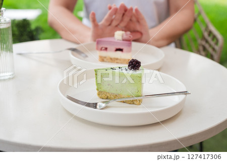 Woman Gesturing Near Colorful Cakes on White Plates in Outdoor Setting. No to sugar, diet concept, fasting, dieting, losing weight. No cakes, woman on a diet. 127417306