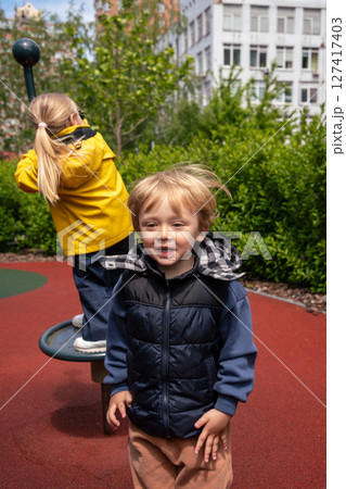 Two children enjoying their time at a vibrant playground on a sunny day. The image captures happiness and outdoor fun while highlighting the youthful energy of children engaging in play. Two children enjoying their time at a vibrant playground on a sunny day. The image captures happiness and outdoor fun while highlighting the youthful energy of children engaging in play. 127417403
