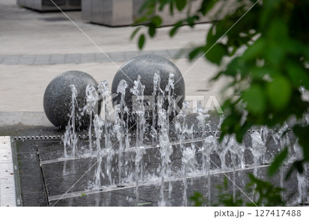 Outdoor decorative fountain with round marble sculptures and flowing water streams. Outdoor decorative fountain with round marble sculptures and flowing water streams. 127417488
