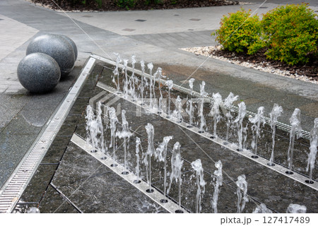 Outdoor decorative fountain with round marble sculptures and flowing water streams. 127417489
