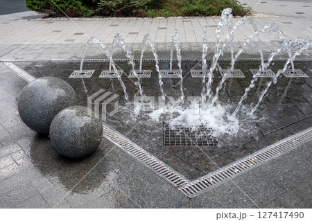 Outdoor decorative fountain with round marble sculptures and flowing water streams. 127417490