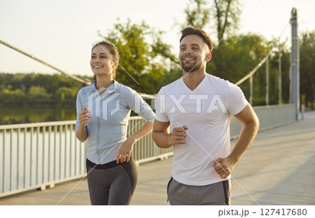 Morning run of happy active couple of runners, confident woman and man running together outdoor Morning run of happy active couple of runners, confident woman and man running together outdoor 127417680