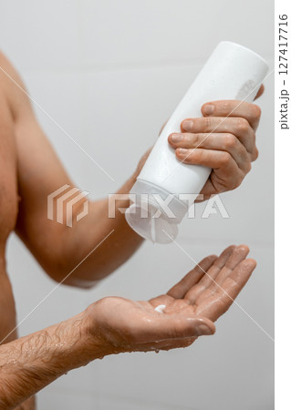Unrecognizable man using lotion in white bathroom 127417716