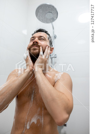 Brunette man washing head with shampoo in bathroom 127417717