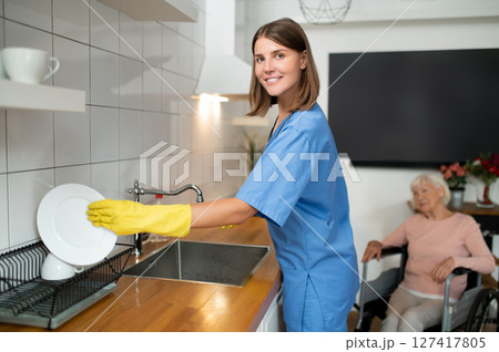 Young nurse cleaning the kitchen in the elderly woman house 127417805