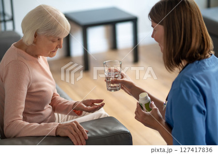 Care assistant giving medicine to an elderly woman Care assistant giving medicine to an elderly woman 127417836