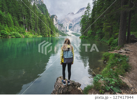 Young woman with backpack on the stone on mountain lake Braies Young woman with backpack on the stone on mountain lake Braies 127417944