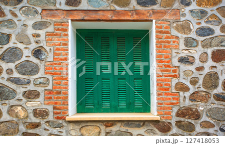Green window shutters decorating a stone and brick wall in a building 127418053
