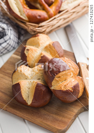 Crunchy bavarian buns on cutting board on kitchen table. Crunchy bavarian buns on cutting board on kitchen table. 127418265